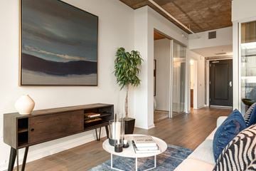 San Diego apartment for rent - A living room with a painting on the wall and a plant on the side table.