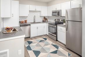 Tigard apartment for rent - A kitchen with white cabinets and a rug on the floor.