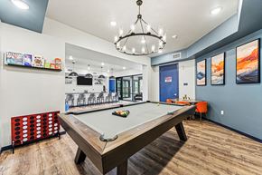Colorado Springs apartment for rent - A pool table is in the middle of a room with a blue wall and a chandelier hanging from the ceiling.
