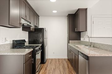 San Marcos apartment for rent - A kitchen with brown cabinets and a black fridge.