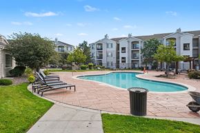 Lakewood apartment for rent - A swimming pool surrounded by a grassy area and apartment buildings.