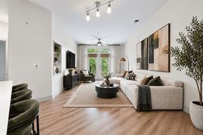 Herndon apartment for rent - A modern living room with a large couch, a coffee table, and a potted plant.