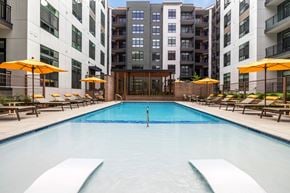 Ashburn apartment for rent - A swimming pool surrounded by lounge chairs and umbrellas in front of apartment buildings.