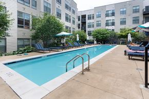 Arlington apartment for rent - A swimming pool surrounded by chairs and umbrellas in a residential area.