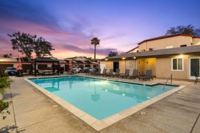 San Marcos apartment for rent - A pool surrounded by chairs and a building in the background.