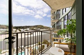 Los Angeles apartment for rent - A balcony with a table and chairs overlooking a pool and a hillside.