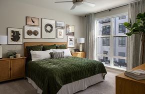 Annapolis apartment for rent - A bedroom with a bed, a ceiling fan, and a window with a view of a building outside.