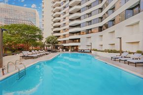 Arlington apartment for rent - A large swimming pool in front of a building with lounge chairs on the side.