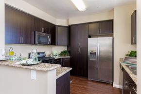 San Diego apartment for rent - A kitchen with dark brown cabinets and a granite counter top.