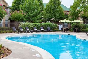 Baytown apartment for rent - A pool surrounded by trees and chairs.