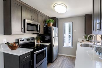 An empty kitchen with black appliances and white counter tops