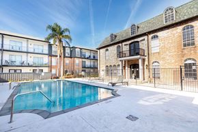 Metairie apartment for rent - A swimming pool is surrounded by a fence and a building.