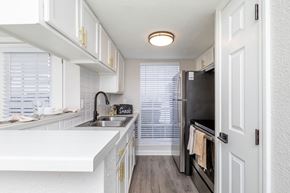 Metairie apartment for rent - A kitchen with white cabinets and a black fridge.