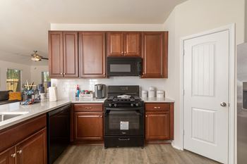 A kitchen with brown cabinets and a black stove.