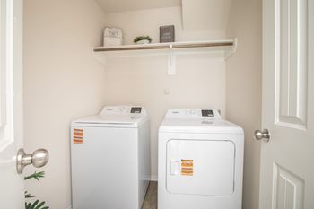 Two white washing machines in a small laundry room.
