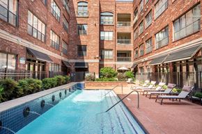 Houston apartment for rent - A pool surrounded by chairs and buildings.