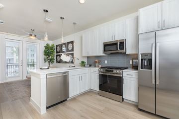 Pearland apartment for rent - A modern kitchen with stainless steel appliances and white cabinets.