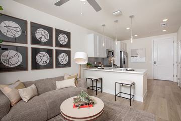 Pearland apartment for rent - A living room with a grey couch and a coffee table with a plant on it.