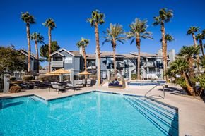 Las Vegas apartment for rent - A resort-style pool surrounded by palm trees and lounge chairs at The Layne at Peccole Ranch modern apartments in Las Vegas.