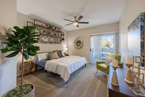 Las Vegas apartment for rent - A bedroom with a bed, chair, and a plant.