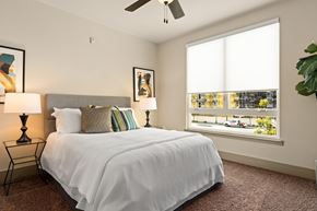 Anaheim apartment for rent - A bedroom with a large bed and a window overlooking a street.