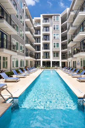 Austin apartment for rent - A large swimming pool in front of a multi-story residential building.