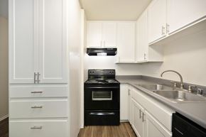 Escondido apartment for rent - a studio apartment kitchen with white cabinets and a black oven and sink