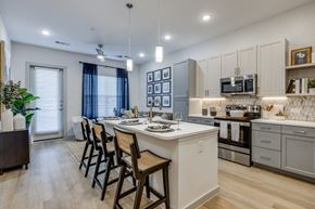 Celina apartment for rent - A kitchen with a white island and wooden chairs.