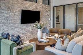 Celina apartment for rent - A living room with a green couch, a coffee table, and a flat screen TV mounted on a brick wall.