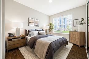 Waldorf apartment for rent - A bedroom with a large bed and a window overlooking a cityscape.