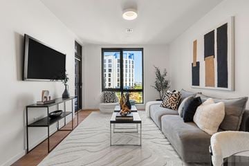Brighton apartment for rent - A modern living room with a grey couch and a flat screen TV mounted on the wall.