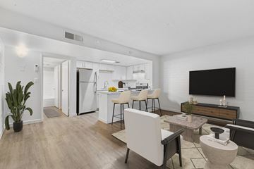 Phoenix apartment for rent - A modern living room with a white chair and a television on the wall.