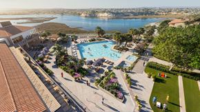 Newport Beach apartment for rent - A large outdoor swimming pool surrounded by a grassy area and trees.