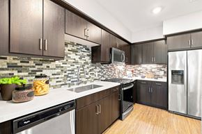 San Diego apartment for rent - A kitchen with dark brown cabinets and a backsplash of stone tiles.