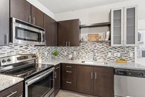 San Antonio apartment for rent - A kitchen with brown cabinets and a black and white tiled backsplash.