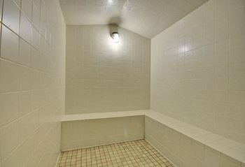 A white tiled shower with a shower head.