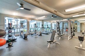 Austin apartment for rent - A spacious gym with various exercise equipment and a fan.
