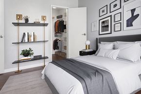 Philadelphia apartment for rent - A bedroom with a bed, a shelf with books and a plant, and a wall with framed pictures.
