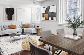Philadelphia apartment for rent - A modern living room with a grey sofa, a wooden table, and a woven chair.