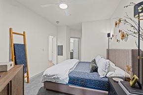 Prosper apartment for rent - A bedroom with a bed, a mirror, and a ceiling fan.