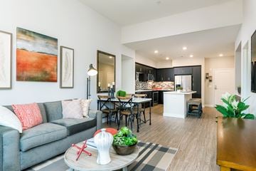 San Diego apartment for rent - A modern living room with a grey couch and a dining area in the background.