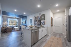 Denton apartment for rent - A kitchen with a refrigerator on the right and a dining table with chairs in the middle.
