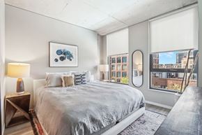 Chicago apartment for rent - A bedroom with a large bed and a view of the city.