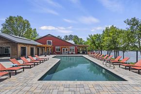 Boise apartment for rent - A pool surrounded by red lounge chairs and a wooden building.