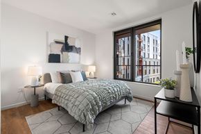 Brighton apartment for rent - A bedroom with a large bed and a window overlooking a city.
