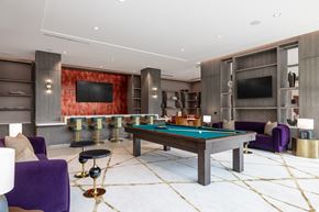 Washington apartment for rent - A billiard table is surrounded by purple chairs in a room with a red wall.