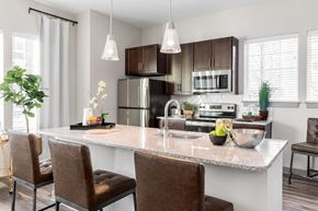 Ronkonkoma apartment for rent - A modern kitchen with brown chairs and a marble countertop.