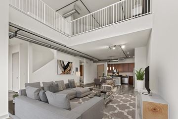 Los Angeles apartment for rent - A living room with a grey couch and a television on a wooden stand.