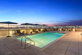 Anaheim apartment for rent - A swimming pool on a rooftop with a sunset in the background.