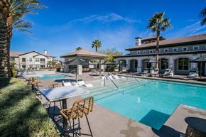 Las Vegas apartment for rent - A pool with chairs and a table in front of a house.